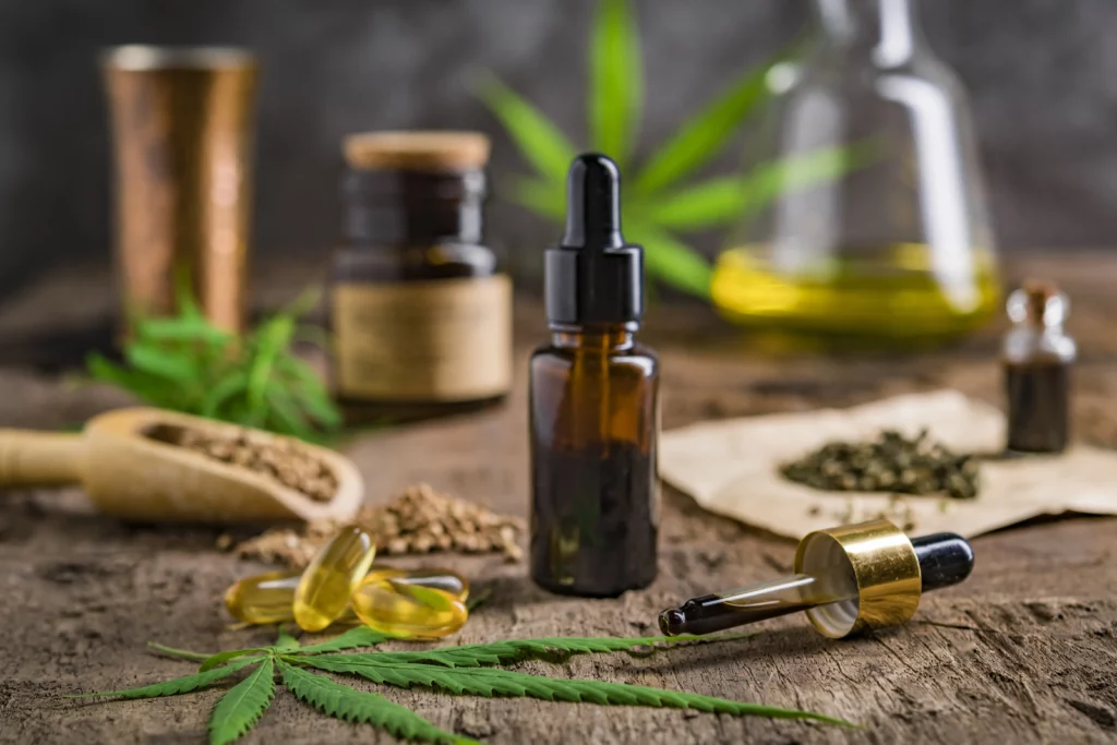 Productos de CBD (aceite, cápsulas) y hojas y semillas de cáñamo sobre una mesa.